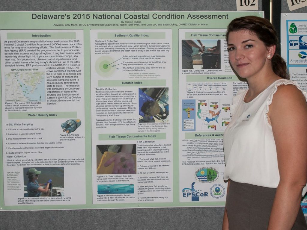 Photo of a student standing by her research poster